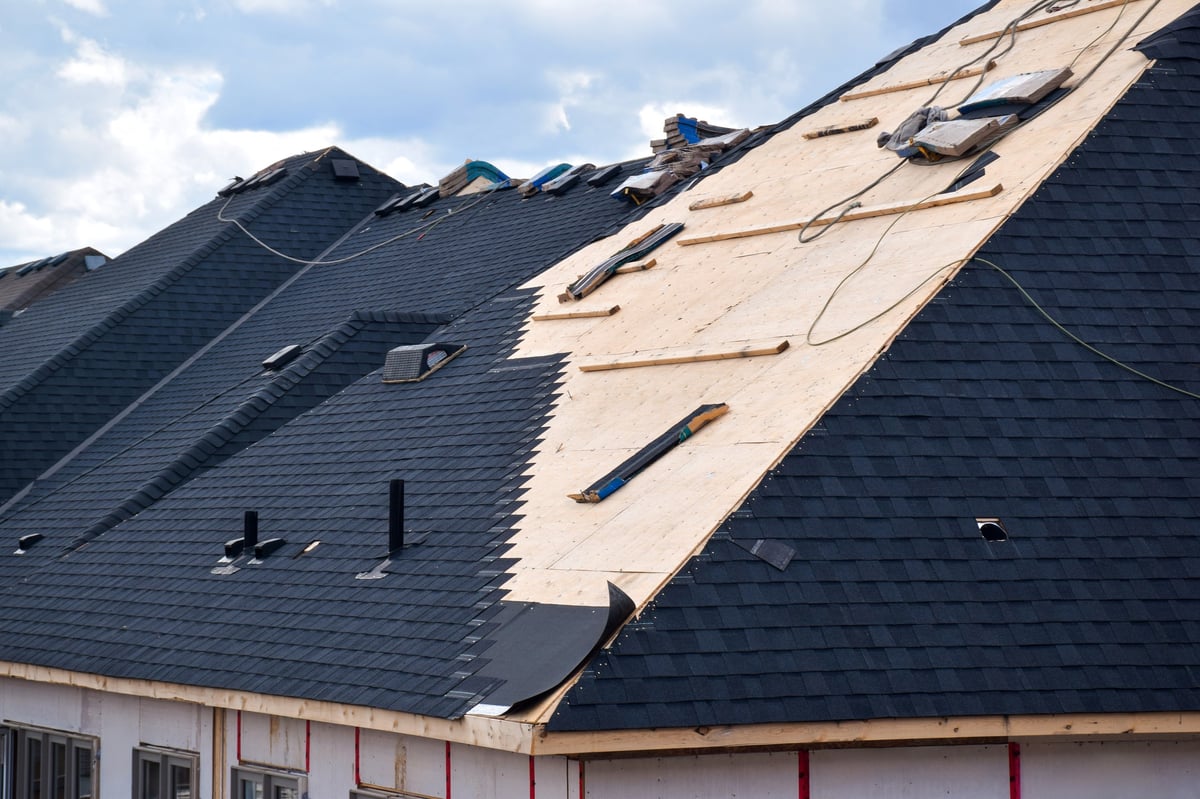 Closeup installation of black roof shingles on new home